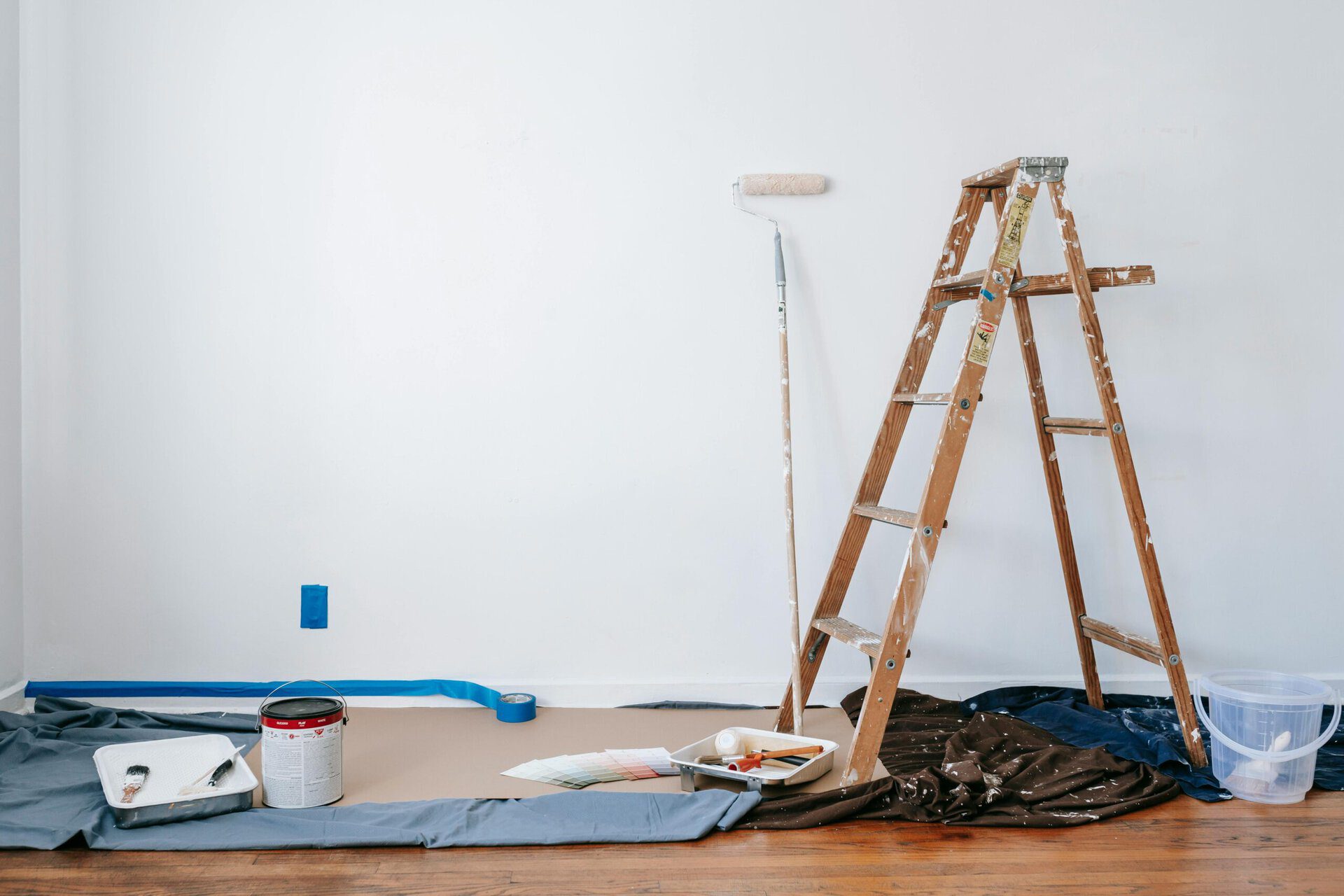 Room undergoing renovation with ladder, paint cans, and tools scattered on the floor.
